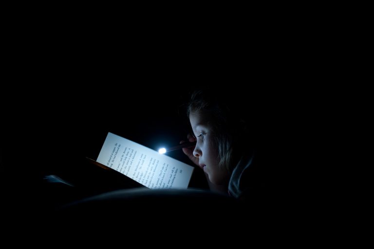 Girl Reading Book with Small Flashlight